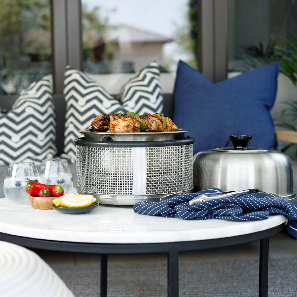 COBB Portable Cooker on a patio table cooking chicken and peppers