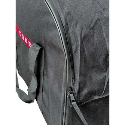 Close-up of a black fabric bag with a red and white COBB logo patch, a gray webbed handle, and a dark zipper.