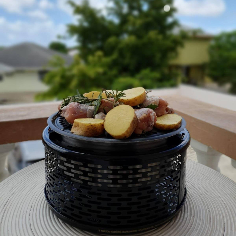 Black COBB PRO GRILL with food on a table outdoors