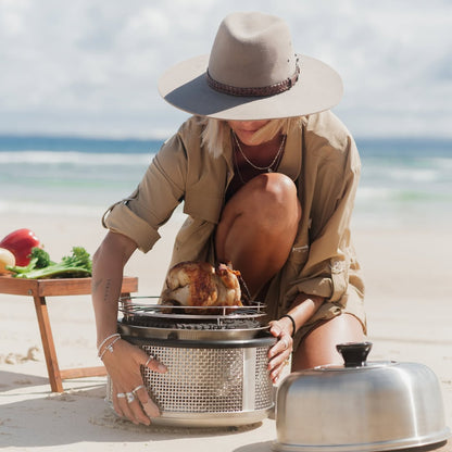 COBB Ultimate portable cooker on beach with person holding COBB
