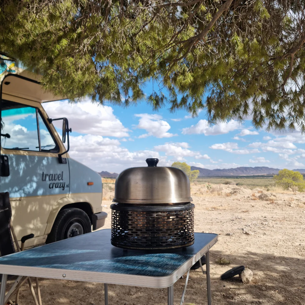 cobb pro portable grill on table under tree with campervan in background