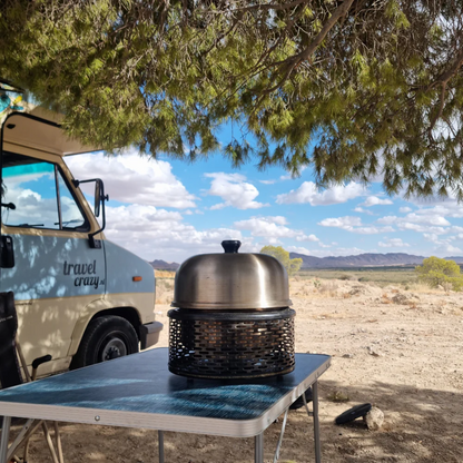 cobb pro portable grill on table under tree with campervan in background